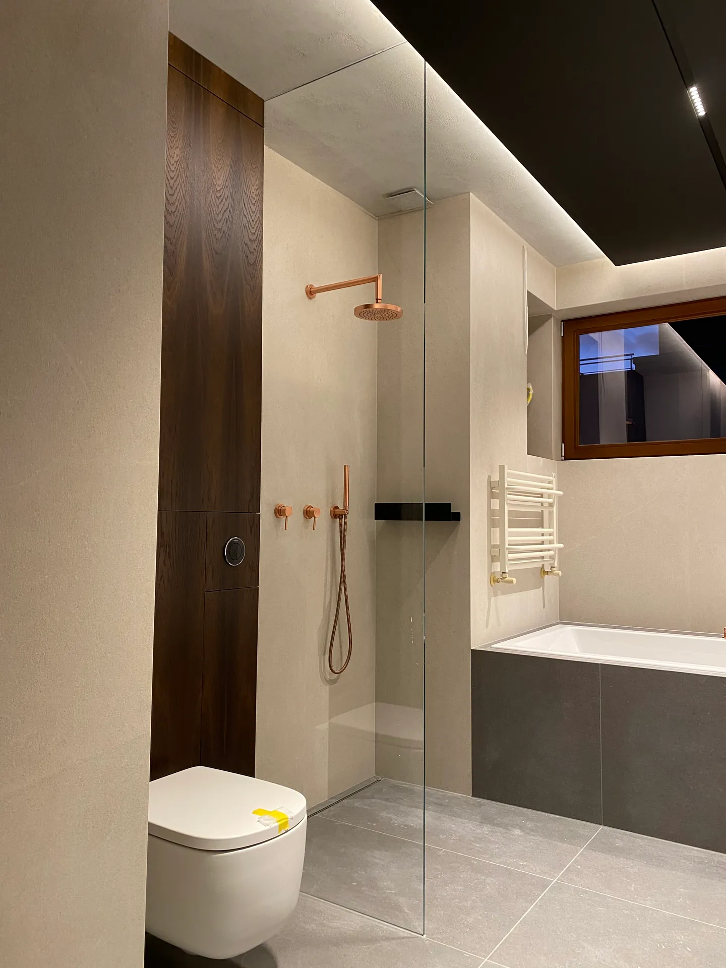 Bezramowa szyba walk-in przy wannie w łazience z miedzianą armaturą