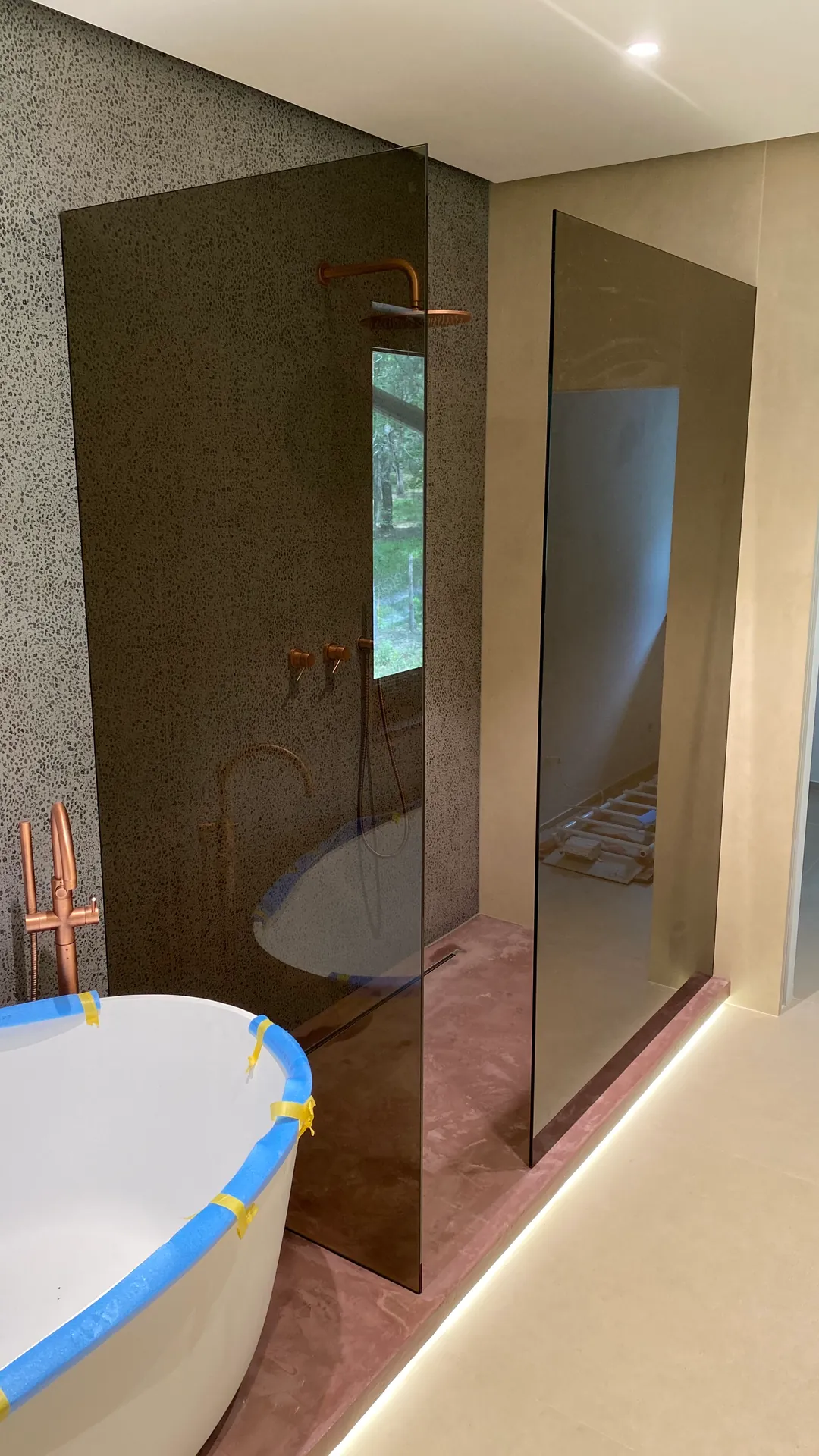Przyciemniane szyby walk-in przy wannie wolnostojącej i miedzianej armaturze